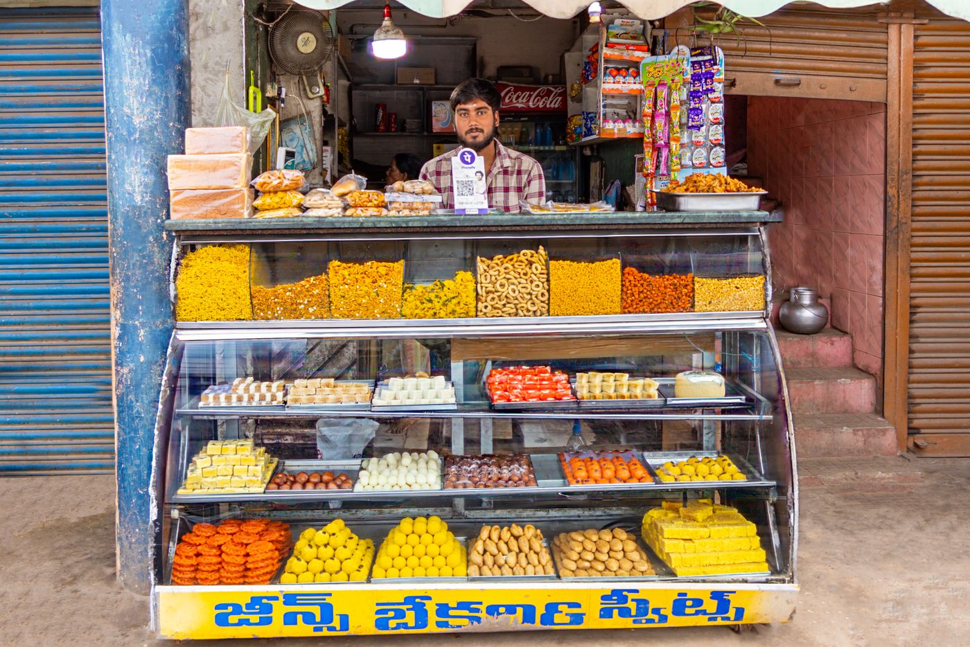 A sweet shop counter with trays of mithai laid out