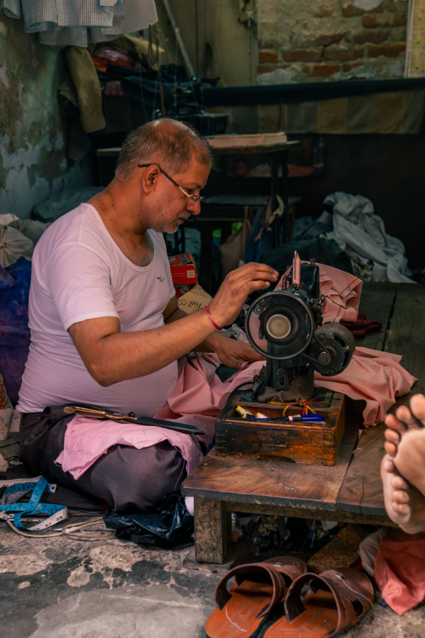 A tailor working at a sewing machine in a small workshop